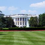 Iconic view of the White House with lush gardens and a central fountain on a sunny day.